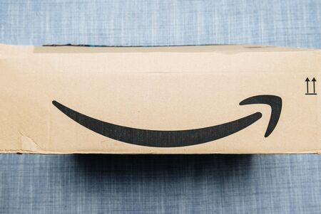 Paris, France - Jun 11, 2018: Freshly delivered Amazon Prime cardboard box featuring big smile on the textile couch backgroundのeditorial素材