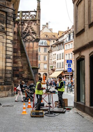 Paris, France - June 13, 2018: Team working near open sewage manhole hole - internet provider company working on implementation of fiber optic cables in French city public internet network infrastructureのeditorial素材
