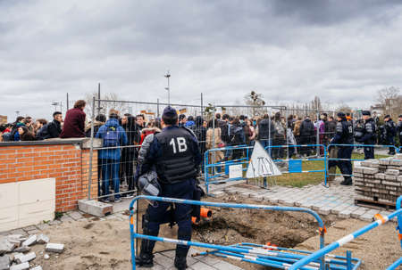STRASBOURG, FRANCE - MAR 15, 2019: Police officer looking at protesters separated by fence near European Parliament during demonstrations against climate change global movement Fridays for Futureのeditorial素材