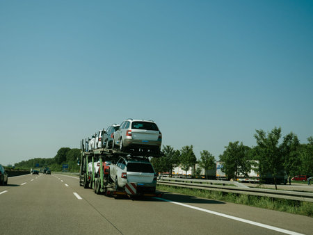 Germany - May 11, 2018: View of long truck transporting new Skoda Volskwagen cars and riding on highway in sunlight under blue sky - cars protected in plastic filmのeditorial素材