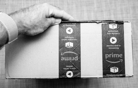 Paris, France - Jun 11, 2018: Man hand holding cardboard box with Amazon Prime logotype and sealed...