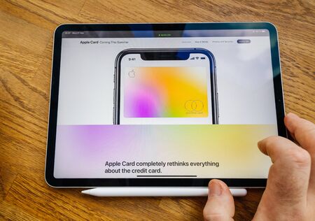 Paris, France - Mar 27, 2019: Man POV at iPad Pro tablet reading on Apple.com website about new Apple Card - colorful titanium credit cardのeditorial素材
