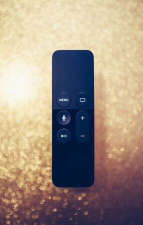 Paris, France - 25 Mar 2019: Modern sparkle holiday fade background with remote control of Apple TV 4k player with Siri assistant browsing Apple TV plus subscription film series documentariesのeditorial素材