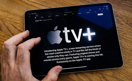 Paris, France - Mar 27, 2019: POV man reading on iPad Pro about Apple TV Plus streaming serviceのeditorial素材