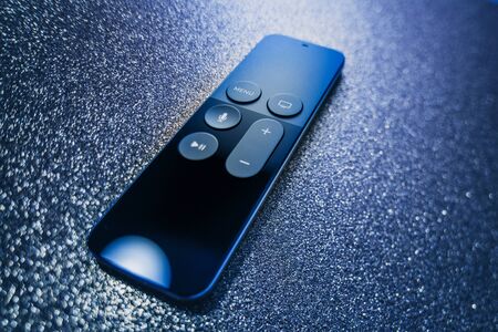 Paris, France - 25 Mar 2019: Modern sparkle holiday blue background with remote control of Apple TV 4k player with Siri assistant browsing Apple TV plus subscription film series documentariesのeditorial素材