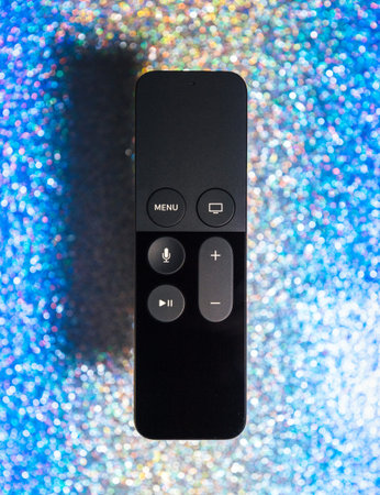 Paris, France - 25 Mar 2019: Modern sparkle holiday blue background with remote control of Apple TV 4k player with Siri assistant browsing Apple TV plus subscription film series documentariesのeditorial素材
