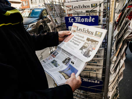 Paris, France - 29 Mar 2019: Newspaper stand kiosk selling press with senior male hand buying latest economical Les Echo featuring news about Peugeot car maker on front coverのeditorial素材