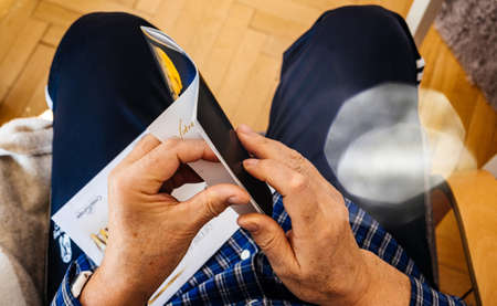 Paris, France - Mar 30, 2019: View from above of senior man opening new advertising leaflet from CroisiEurope Alsace Croisieres until 1997 an international river cruise companyのeditorial素材