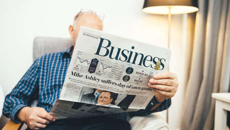 Paris, France - 29 Mar 2019: Senior man reading in living room latest british The Daily Telegraph Business section newspaper UK press featuring Mike Ashley suffers day of own goal