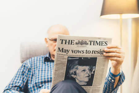 Paris, France - 29 Mar 2019: Senior man reading in living room latest british The Times newspaper UK press featuring Theresa may PM on front cover wows to resign focus on newspaperのeditorial素材