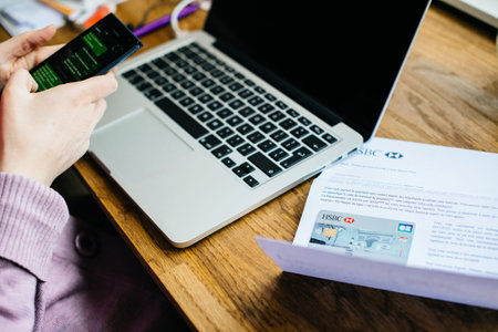 Paris, France - Apr 9, 2017: Woman activating on the smartphone her new HSBC French division featuring Arc de Triumph on the cover Visa Maestro cardのeditorial素材