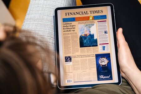 Paris, France - Apr 15, 2019: Woman reading Financial Times on iPad Pro Apple News Plus digital newspaper featuring breaking news on cover French Notre-Dame Cathedral on fire causing damagesのeditorial素材