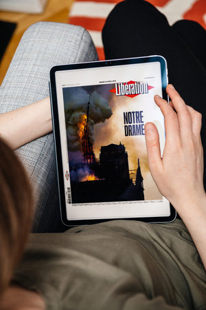 Paris, France - Apr 15, 2019: Woman reading iconic Liberon iPad Pro Apple News Plus digital...