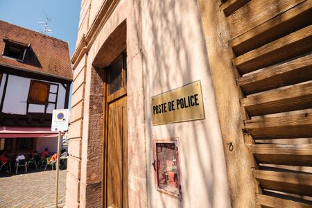 Bergheim, France - 19 Apr 2019: Poste de Police sing in central part of the city with customers of a terrace in the the background enjoying traditional French foodのeditorial素材
