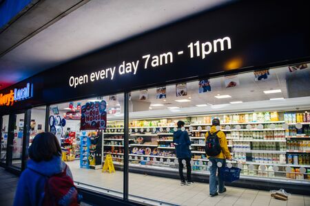 Oxford, United Kingdom - Mar 3, 2017: Woman walking near Sainsburys Local supermarket in central Oxford with customers insideのeditorial素材