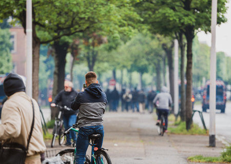 Strasbourg, France - Apr 28, 2019: Rear view of man taking photo on smartphone of police gendarmerie securing Allee de la Robertsau in Strasbourg during Yellow Vests protests in Strasbourgのeditorial素材