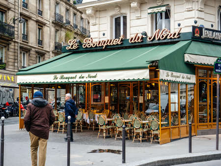 Paris, France - Jan 1, 2018 Typical French cafe restaurant bar pub Le bouquet du nord on Rue de Maubeuge near Gare de Nord train station with pedestrians walking and cars parked nearbyのeditorial素材