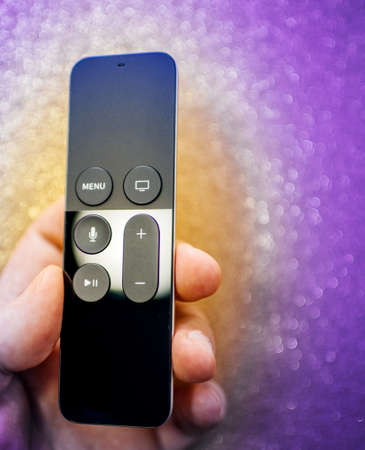 PAris, France - Nov 16, 2018: Man hand holding aginst glitter background Apple Tv 4k remote with integrated Siri assitantのeditorial素材