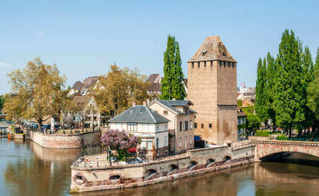 Strasbourg, France - May 5, 2013: Aerial view of tiny alsatian house on the base of les Ponts Couverts Gedeckte Brucken tower cal Ill river and magnolia tree in bloomのeditorial素材