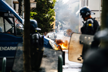 Strasbourg, France - Apr 28, 2019: Silhouette of police officers and street bin fire on Rue Rene...