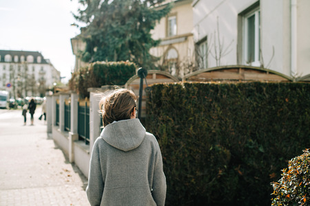 Rear view of young woman in wool coat walking on French street in Strasbourgの写真素材