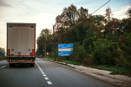 Jucu, Romania - Sep 26, 2013: Romanian highway with large truck cargo haulage near street road sign featuring almost visible NOKIA sign after Nokia Finland closed the factory near Cluj in 2011のeditorial素材