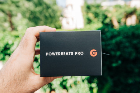 Paris, France - Jun 17, 2019: Man hand holding against green park background Powerbeats Pro Beats by...