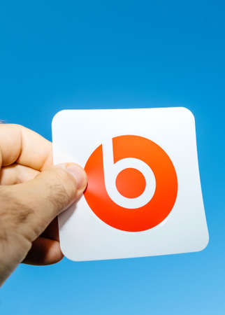 Paris, France - Jun 17, 2019: Man hand holding red sticker with insignia brand during Powerbeats Pro Beats by Dr Dre wireless earphones during unboxing - blue clear sky in the backgroundのeditorial素材