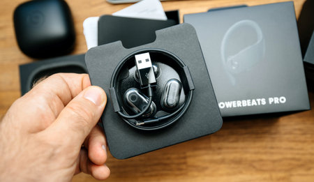 Paris, France - Jun 17, 2019: Man hand holding Eartips with four size options, Lightning to USB-A charging cable for apple Powerbeats Pro Beats by Dr Dre wireless headphones during unboxingのeditorial素材