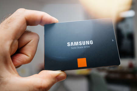 Paris, France - May 18, 2019: man hand holding new SSD Solid state drive disk from Samsung model 860 EVO 1 tb fastest flash media disk - room backgroundのeditorial素材