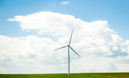 Freshly installed new windmill in green fresh fields in the spring with large cumulus clouds in...