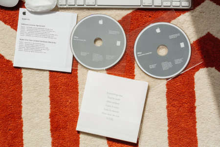 London, United Kingdom - Mar 31, 2014: Parts and components of new iMac 21,5 personal computer made by Apple Computers during unboxing Software license agreement and dvd install software MacOS x dvd diskのeditorial素材