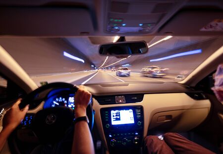 View from the car interior at the windshield and front driving cars inside tunnel - car dashboard defocused light trailsの写真素材