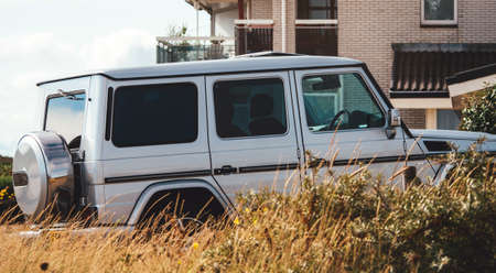 IJmuiden Santpoort Zuid, Netherlands - Aug 20, 2018: Side view of luxury white Mercedes-Benz GElandweagen G500 AMG suv parked in front of the beach house in Dutch coastal villageのeditorial素材