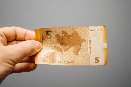 Paris, France - May 19, 2019: Man hand holding against gray background 5 Azerbaijani manat paper currency rear partのeditorial素材