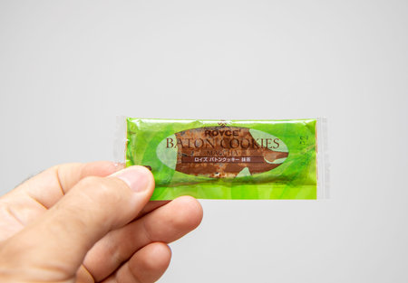 Paris, France - Jul 17, 2019: Man hand holding traditional Japanese Royce Baton Cookies biscuit with...