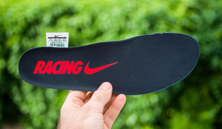 Paris, France - Jul 8, 2019: Man hand POV holding new black NIke Racing running shoe sole against...