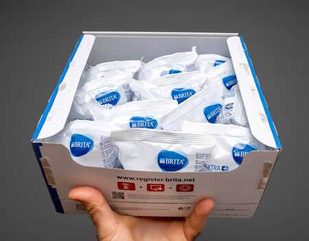 PARIS, FRANCE - JUL 15, 2019: Man holding New Brita water filter cartridge open box against gray backgroundのeditorial素材