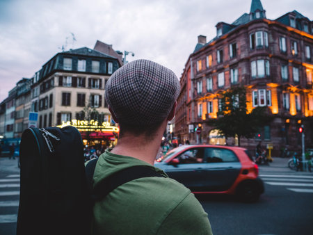 Rear view of unrecognizable adult man with heat looking at the building intersection deciding where to go next in the big French city of Strasbourgの写真素材
