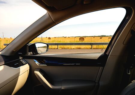 View from the driving car at the yellow fertile fields with round haysの写真素材