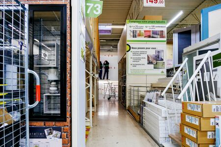 Paris, France - Feb 4, 2019: DIY store with multiple selection of wooden bars f, cardboards with tools, plastic windows and workers installing newest accessory in backgroundのeditorial素材