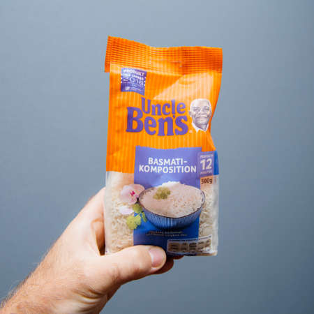 Paris, France - Aug 8, 2018: Man hand holding Uncle Bens basmati rice package against blue backgroundのeditorial素材