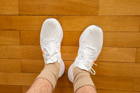 Paris France - Jul 13 2019: Man wearing measuring new Nike Epic React Flyknit 2 running shoes equipment on the living room wooden floor manufactured by Nike sportswearのeditorial素材