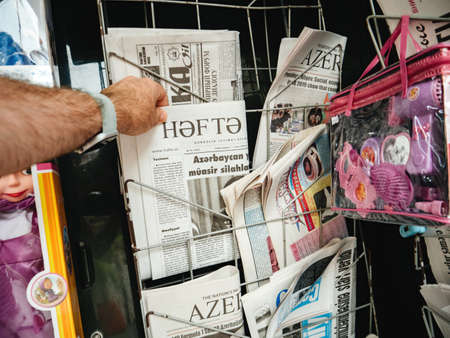 Baku, Azerbaijan - May 3, 2019: man hand buy shop for fresh newspaper Hafta at the press kiosk in central Baku with news about the President Ilham Aliyevのeditorial素材