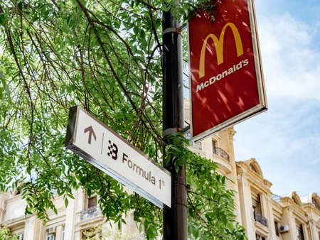 Baku, Azerbaijan - May 2, 2019: McDonalds and Formula 1 sign on the same street pole with Azeri architecture in backgroundのeditorial素材