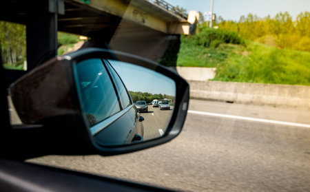 Rear view mirror of a car with multiple cars on a French highway