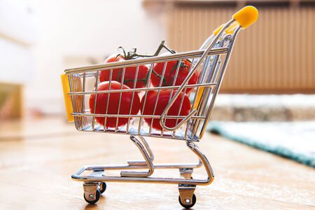 Side view of four bio organic tomatoes in tiny mini supermarket cart - concept of food shopping defocused store backgroundの写真素材