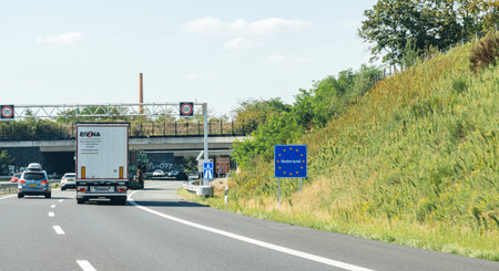 Netherlands - Aug 22, 2019: Truck driving past the Nederland sign at the border between Germany and Netherlands with text on the road sign with European union starsのeditorial素材