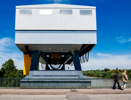 Gambsheim, France - Jun 2, 2013: Pedestrians couple walking in front of Centrale Hydroelectrique de Gambsheim building with Rhine river in backgroundのeditorial素材