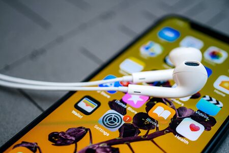 Paris, France - Sep 12, 2019: Apple Computers EarPods on the latest iPhone 11 Pro Smartphone with OLED screen and all apps on home screen in backgroundのeditorial素材